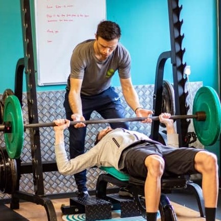 Personal trainer assisting with bench press